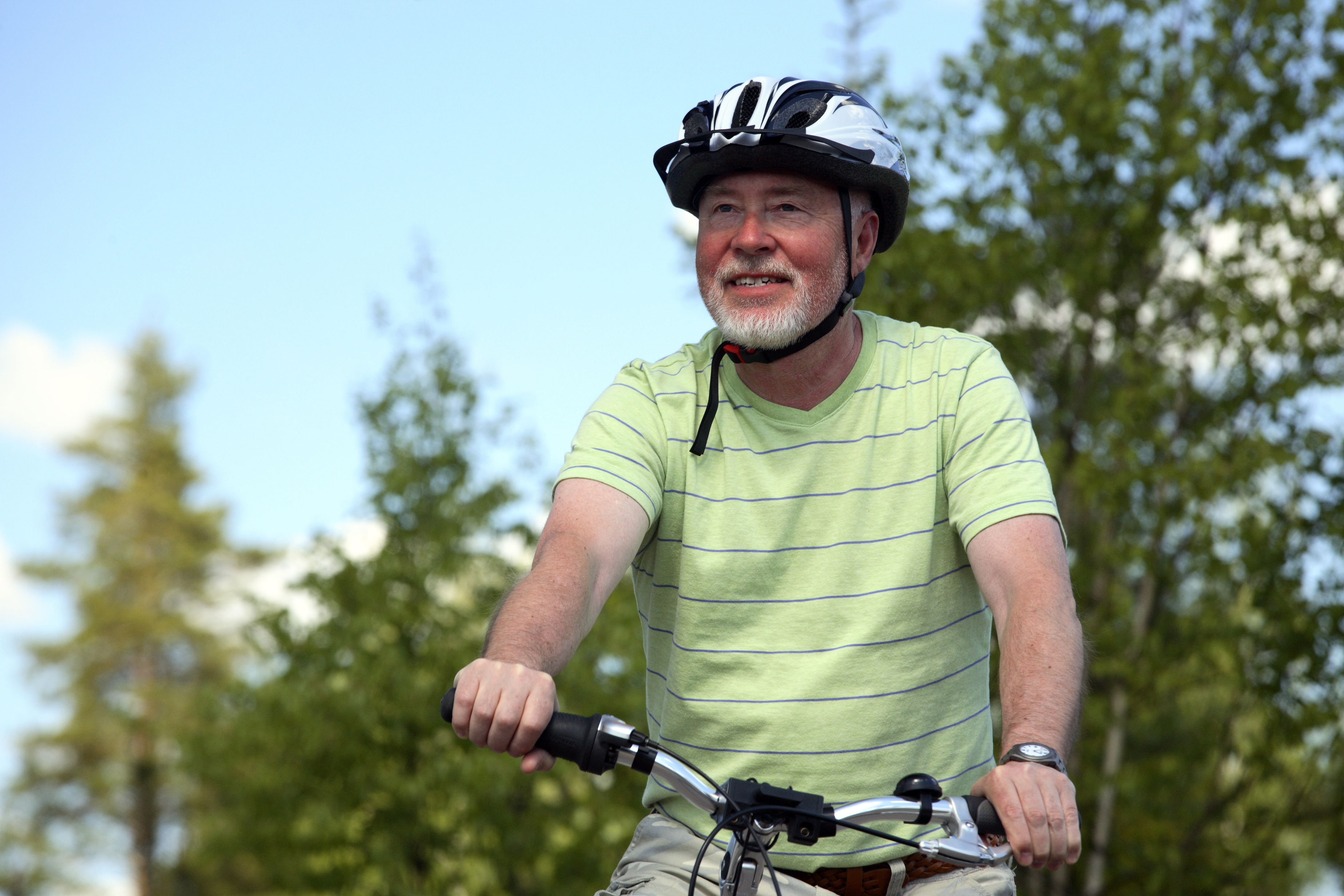På billedet ses en gråskægget mand med cykelhjelm og cykel