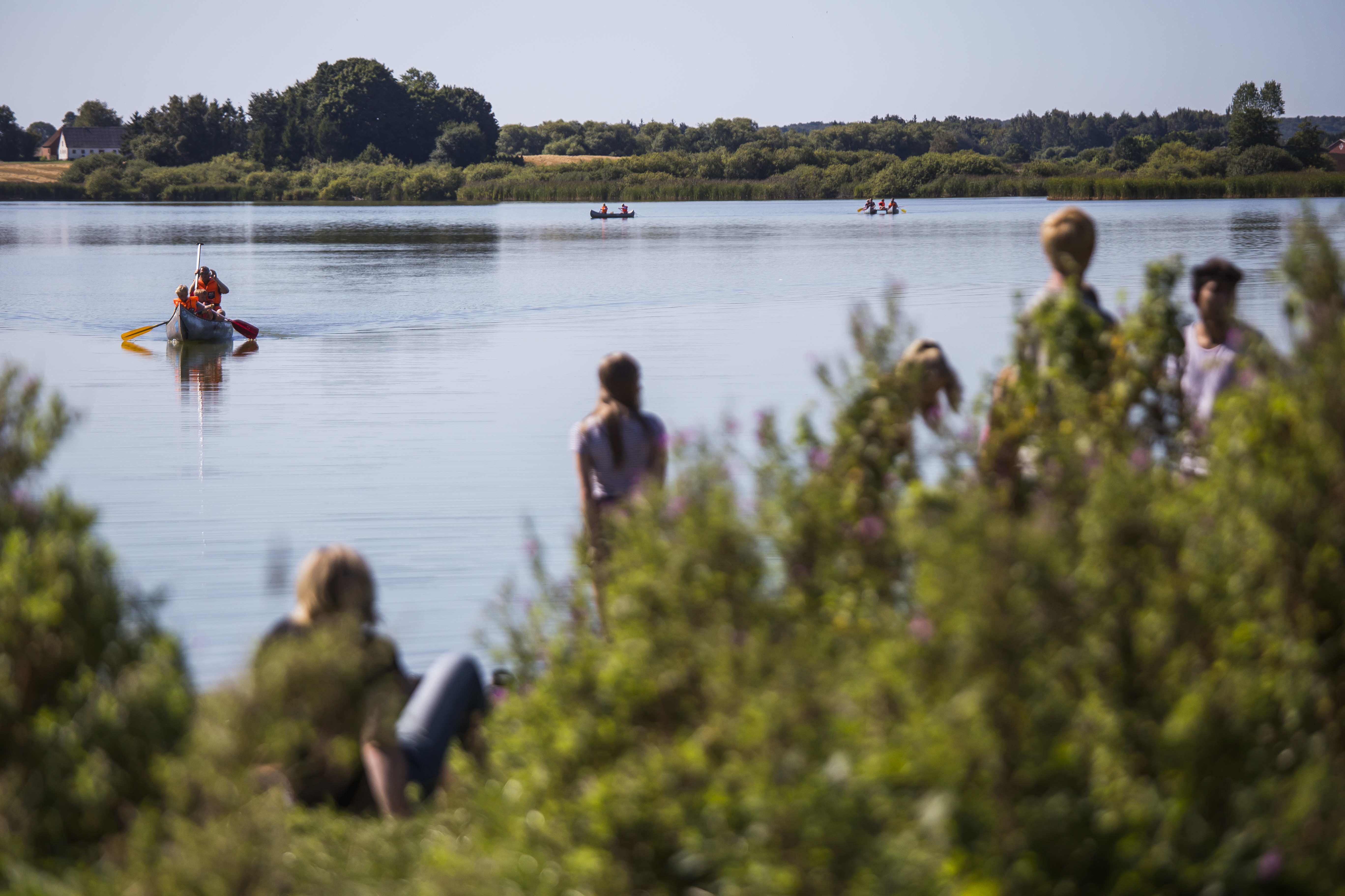 Person sejler i kano på sø i Næstved Kommune, mens folk kigger på