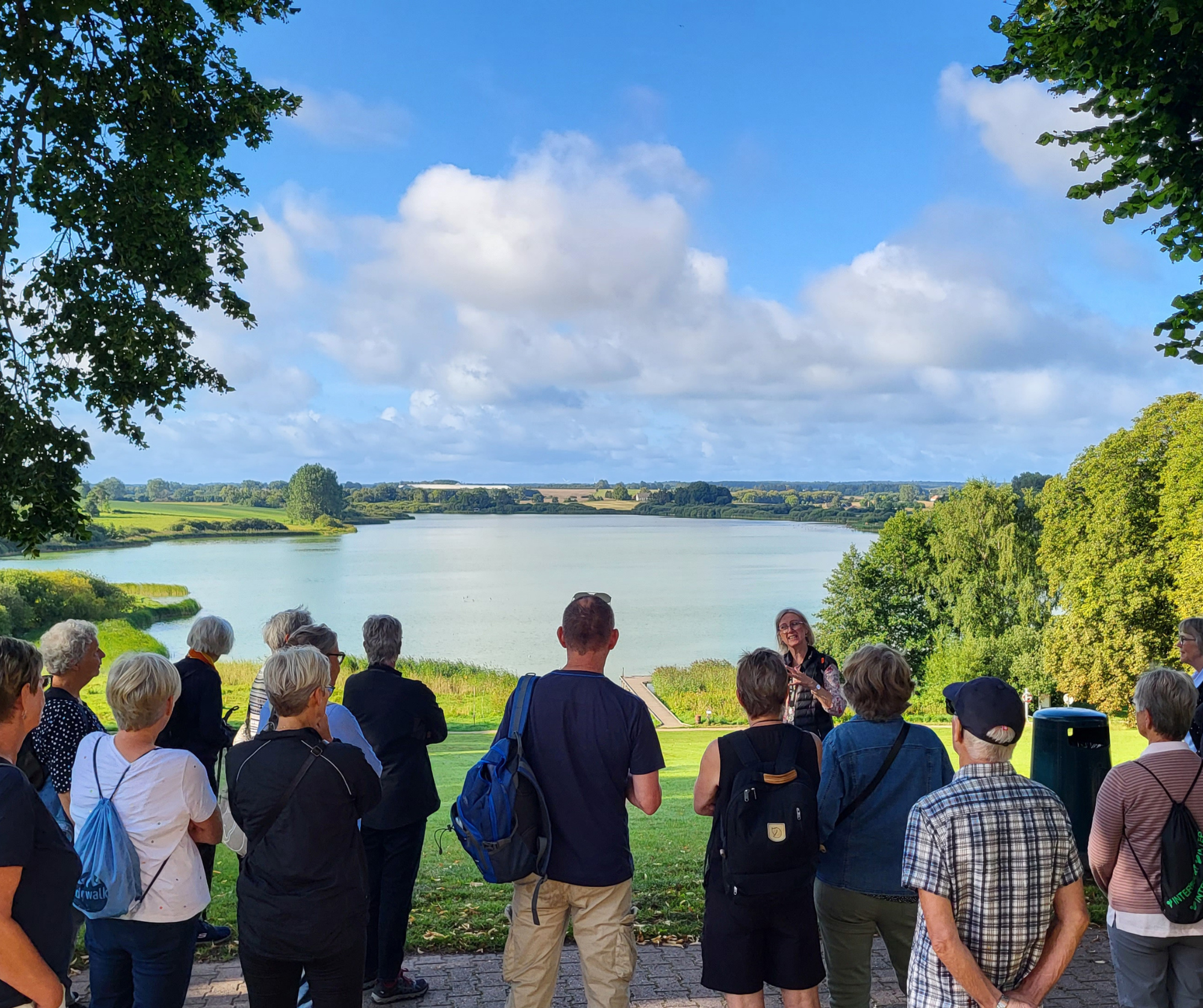Gruppe med personer står ved en sø. 
